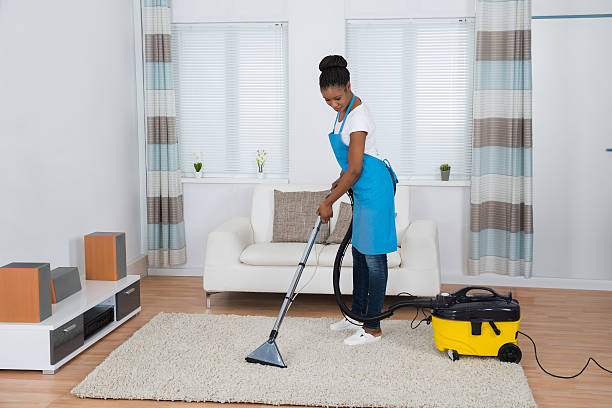 Young African Woman Cleaning Carpet with a Vaccum Cleaner